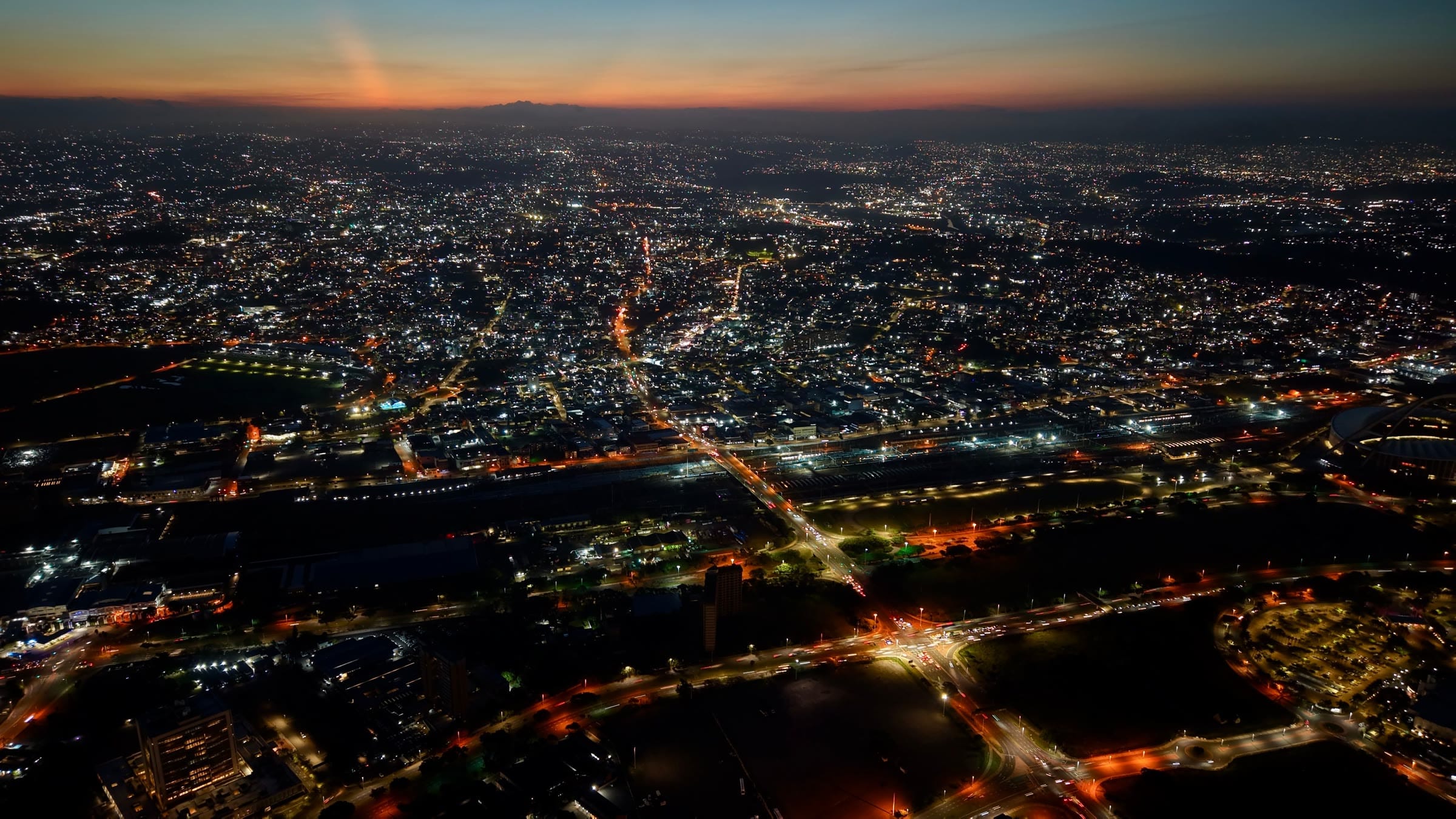Una ciudad vista desde el aire al anochecer, con sus luces extendiéndose hasta el horizonte
