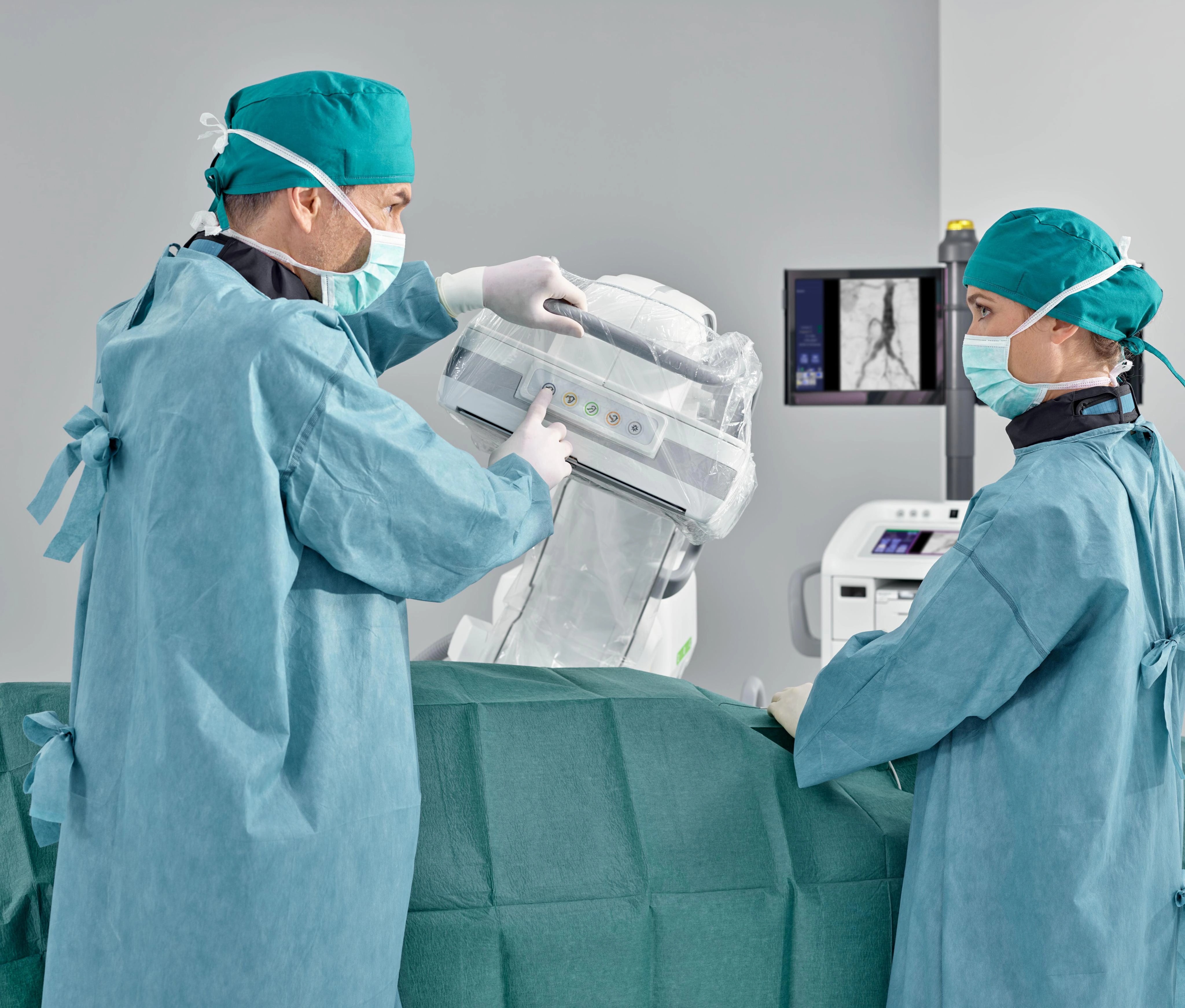 Clinicians adjust the covered Cios Alpha detector beside a draped procedure table, with imaging visible on the monitor.