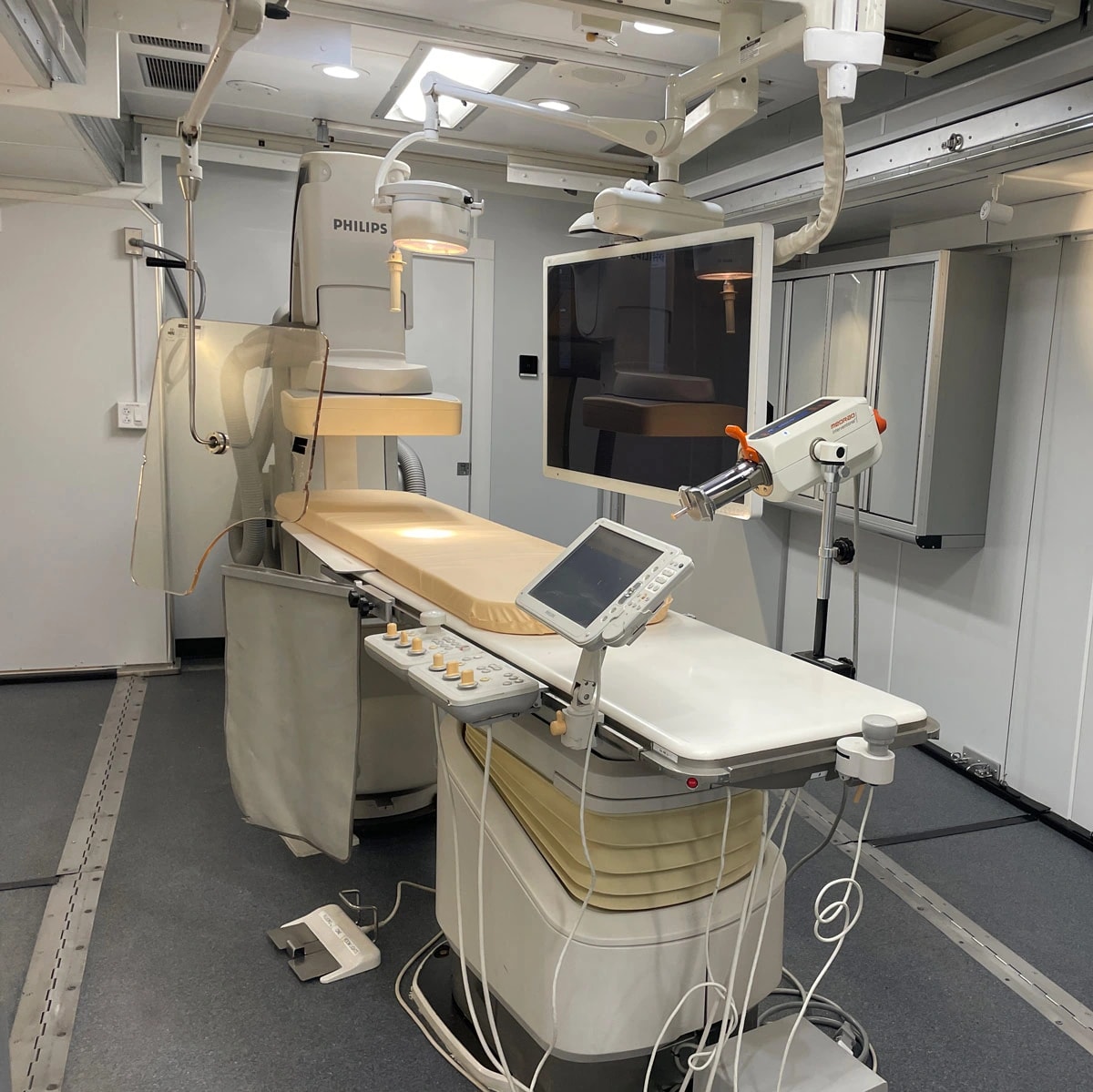 An installed Philips catheterization system, patient table and clinical controls inside a mobile facility.