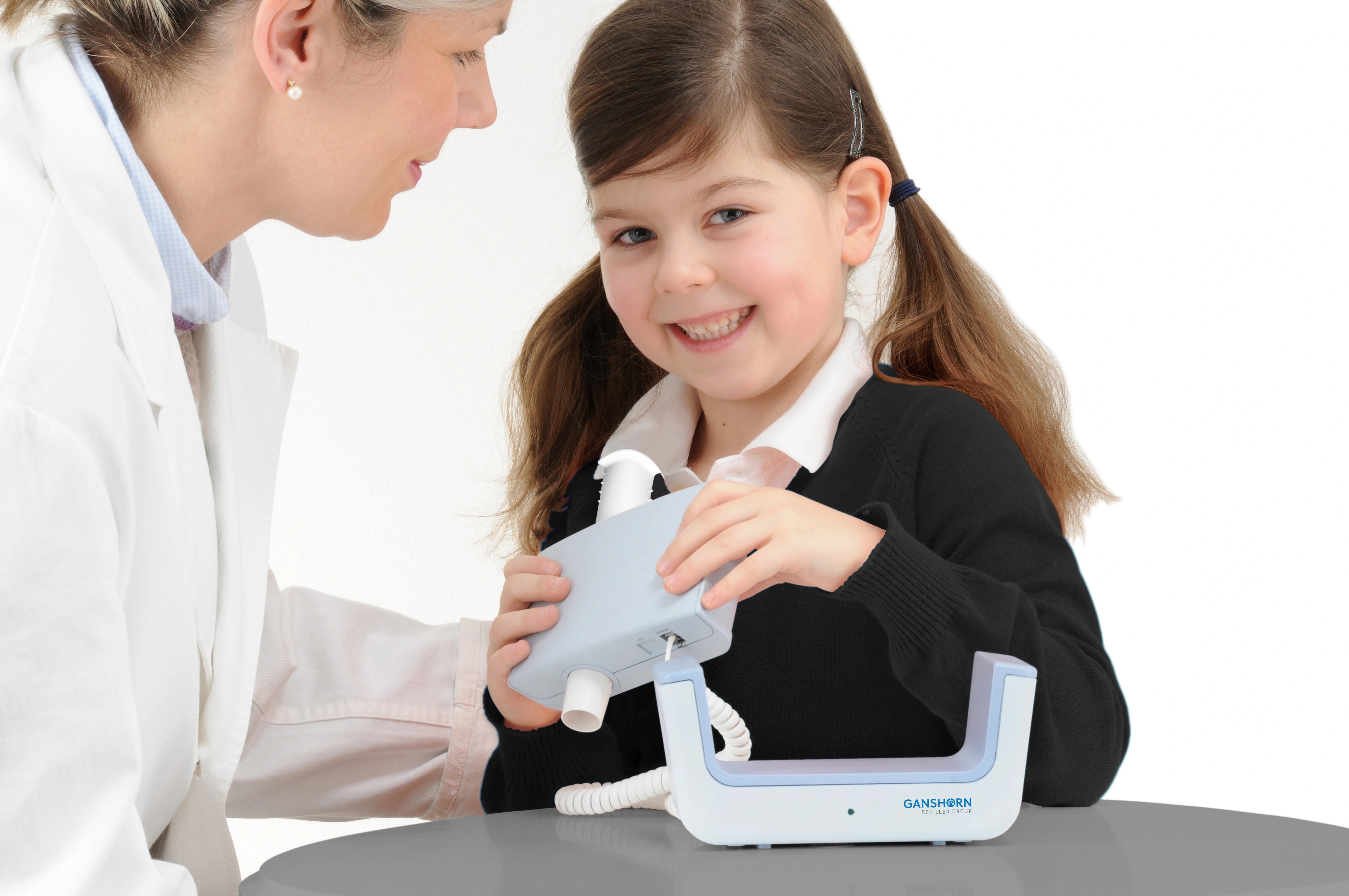 A clinician helps a child prepare a GANSHORN SpiroScout sensor for a spirometry demonstration.