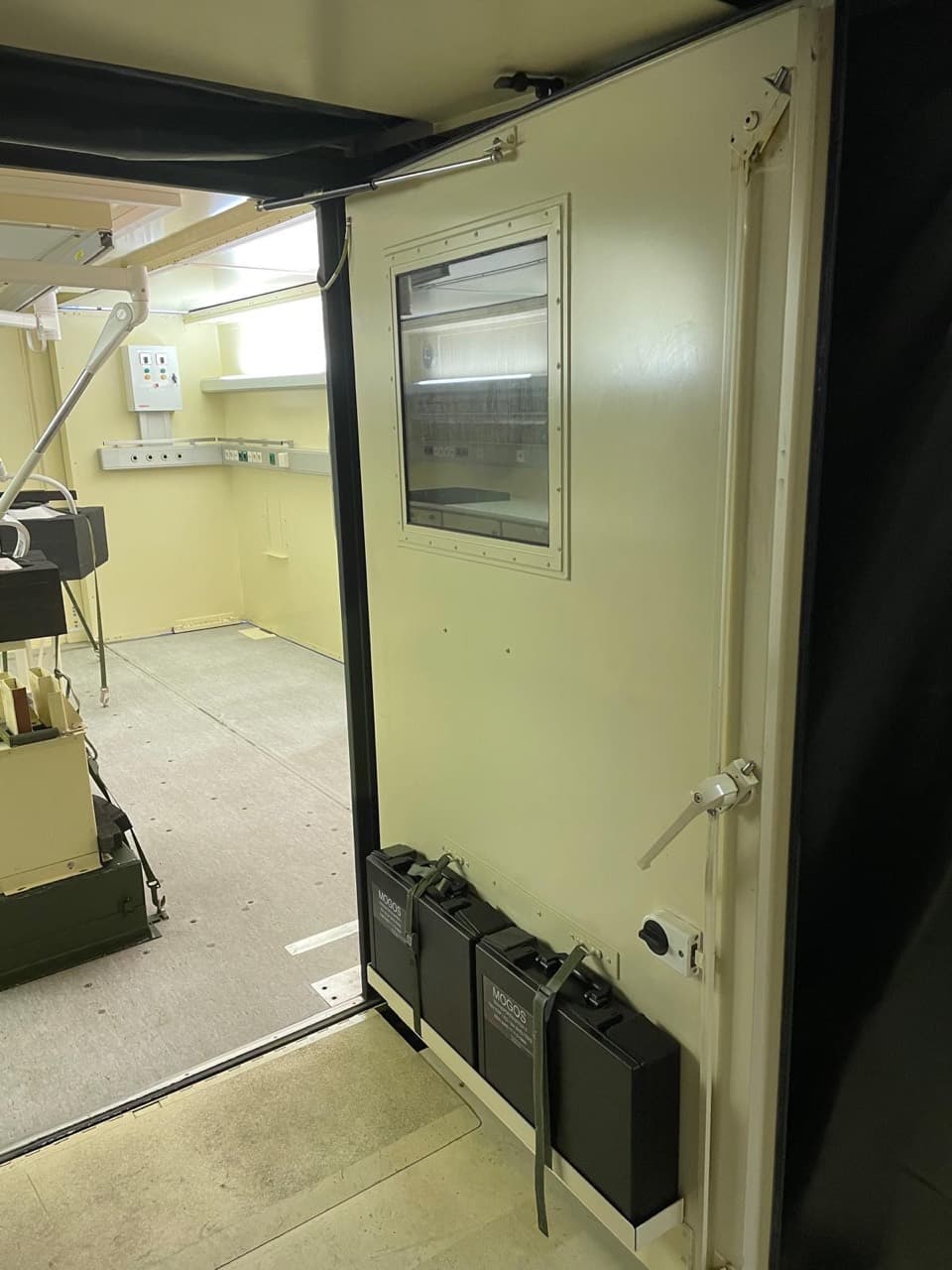 Doorway into a clinical room with transport cases secured beside the entrance