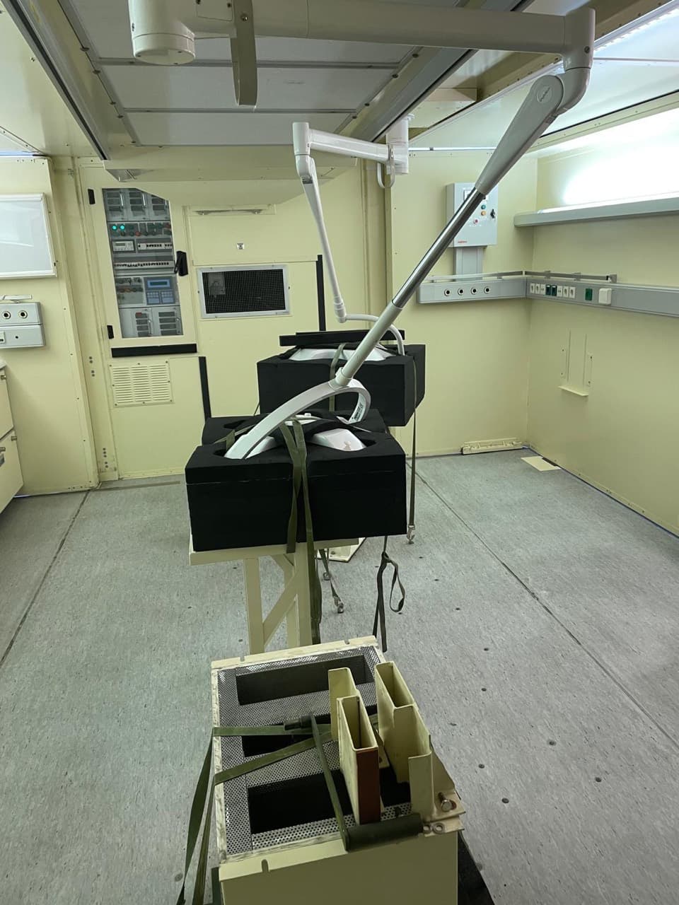 Clinical room interior with ceiling-mounted articulated arms, protected light heads and wall service rails