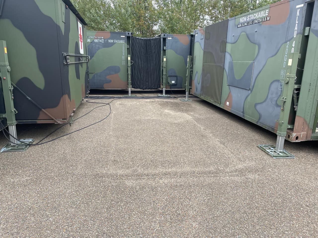 Hospital modules joined by a flexible enclosed connection, with stabilising supports and external cables