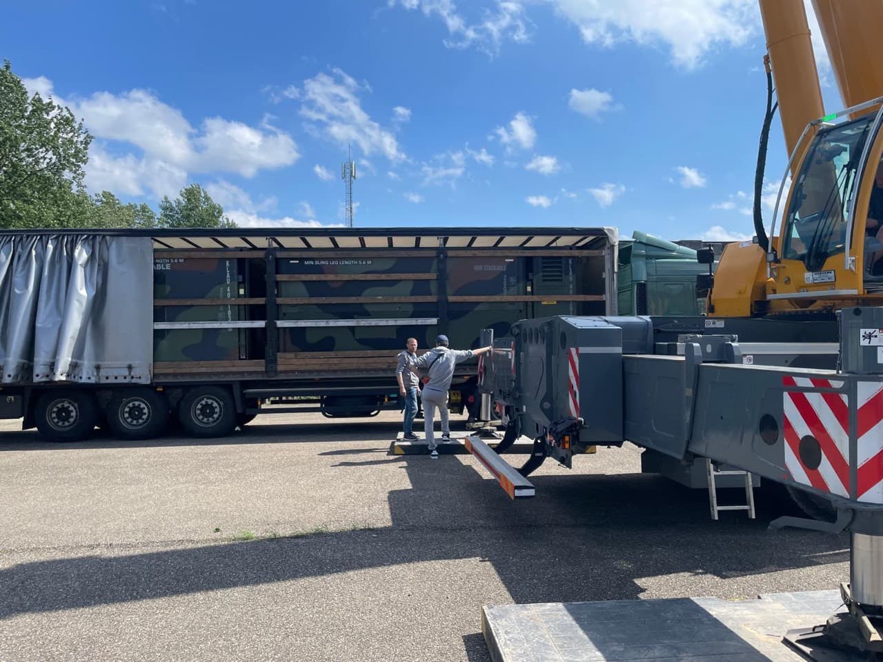 Hospital module on a trailer beside a mobile crane during loading operations