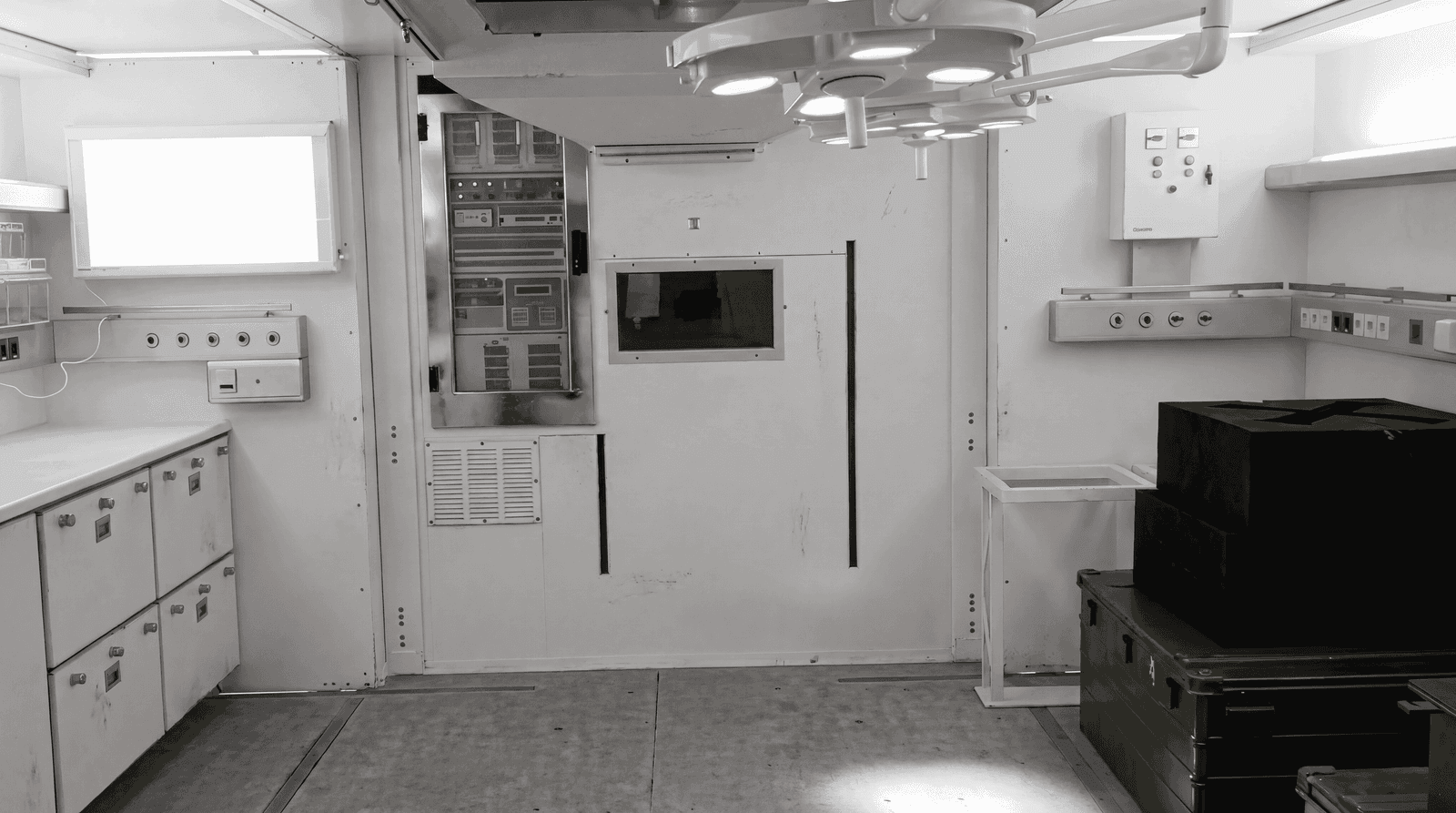 Field hospital operating room with overhead surgical lighting and integrated service panels