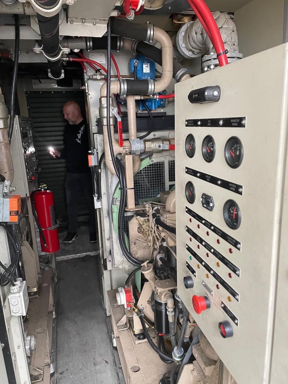 Inside a hospital service module showing pipework, machinery, gauges and a control panel