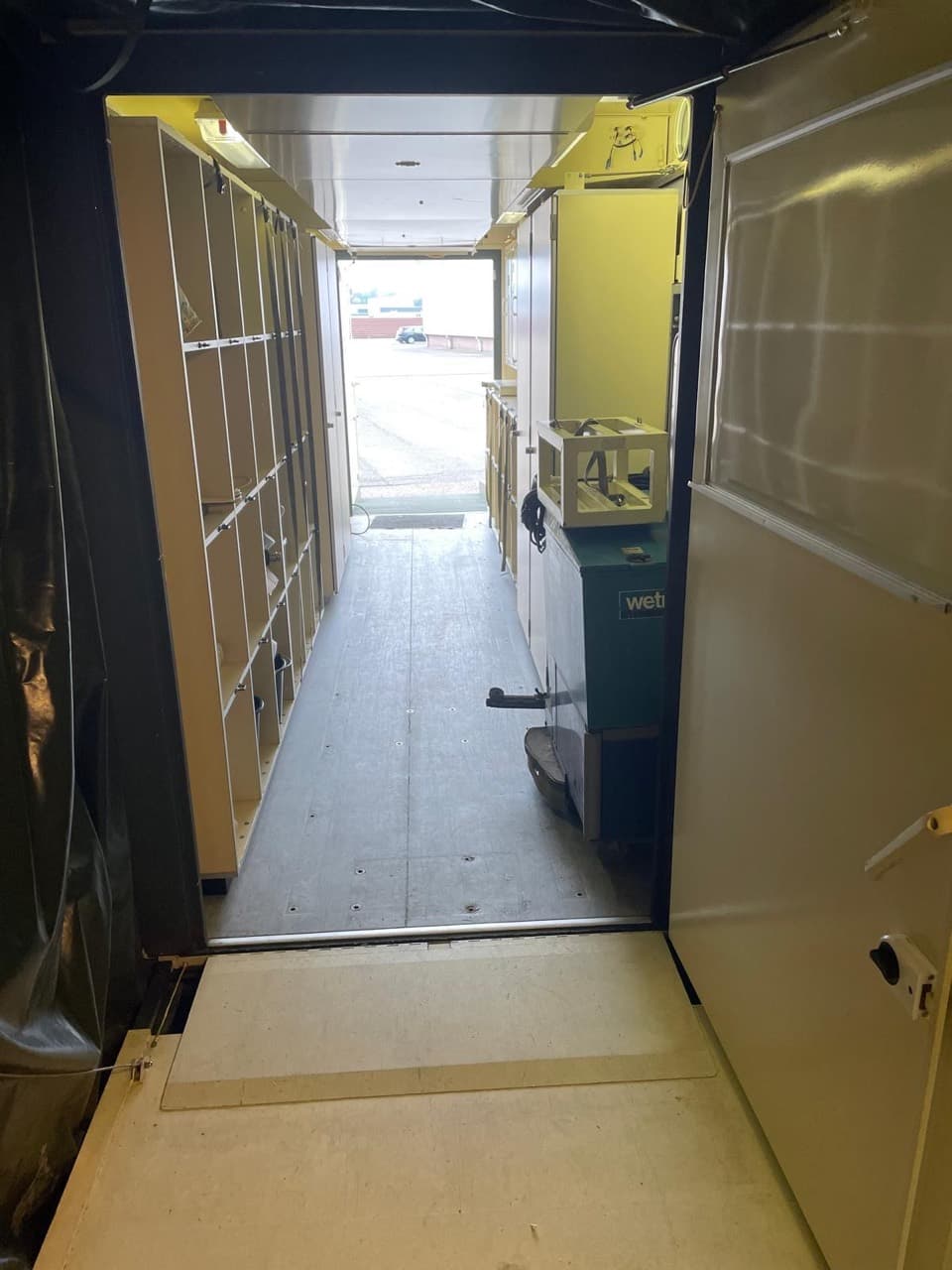 Interior corridor with open storage shelving and an exterior doorway at the far end