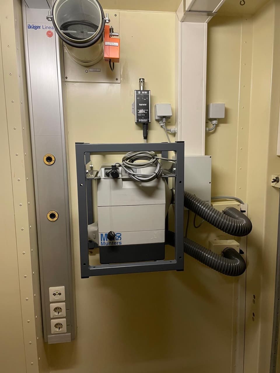 Wall-mounted service equipment with connected ducts beside a power and service panel