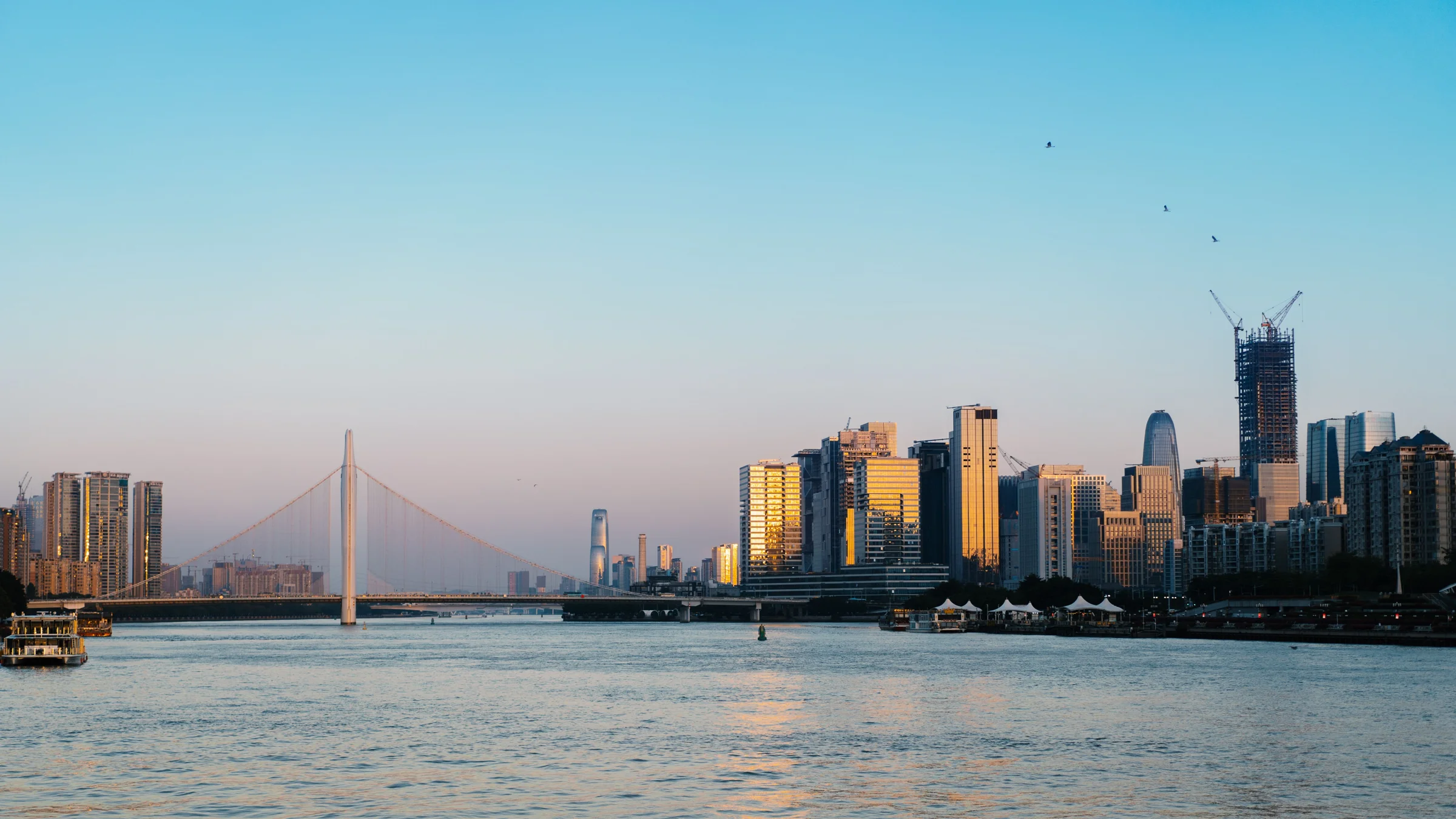 A bridge and city skyline reflected in a river at dusk