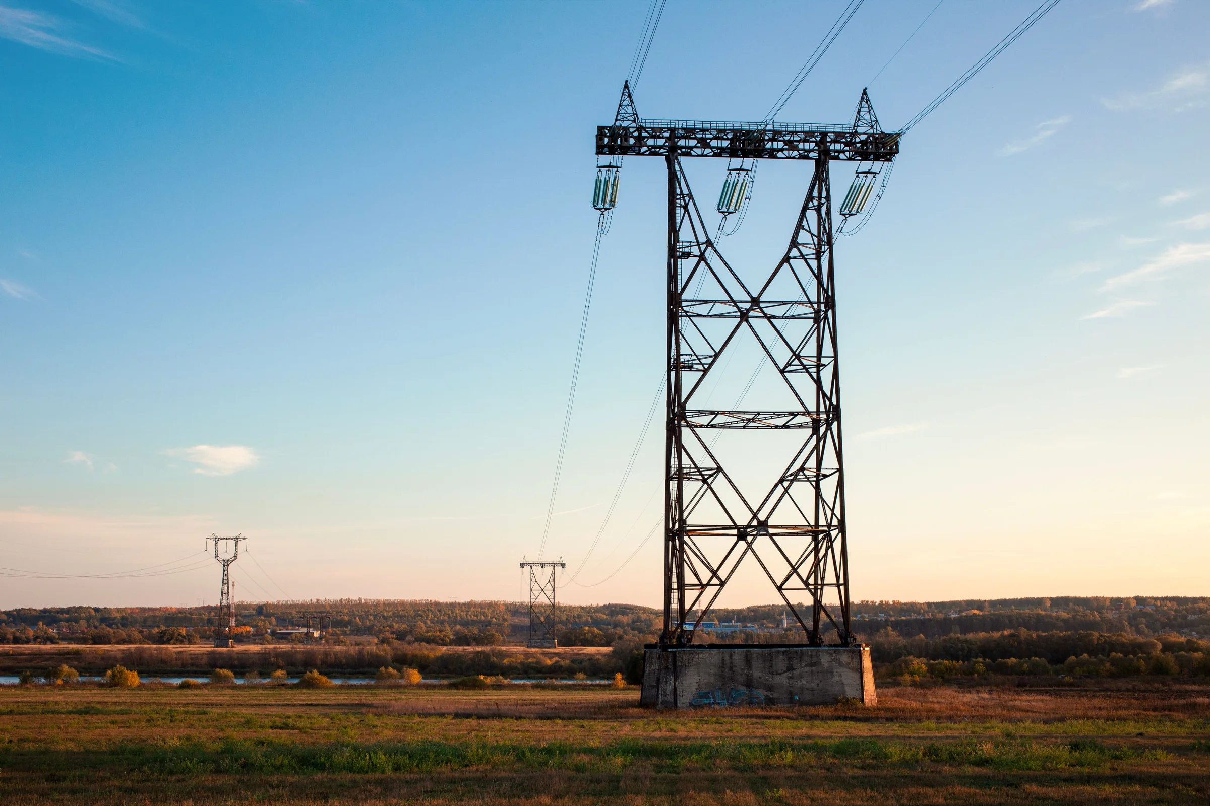 High-voltage transmission towers and power lines across an open landscape