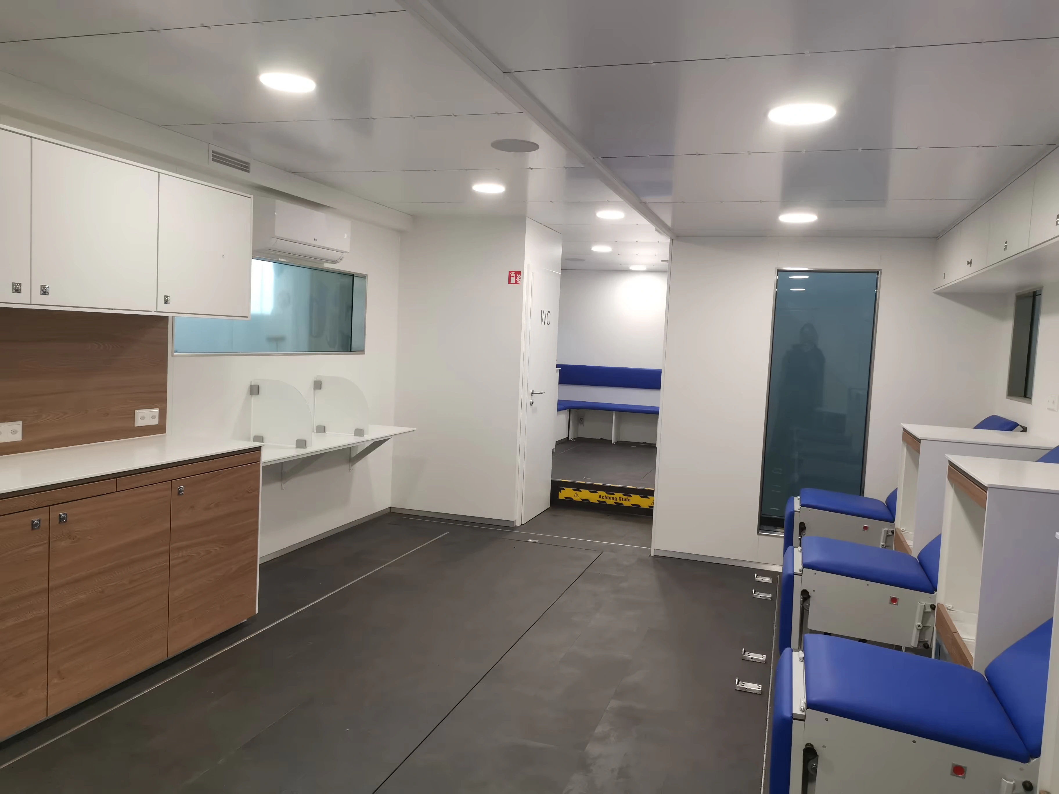 Registration desks, fitted storage and seating in a mobile blood-collection interior.