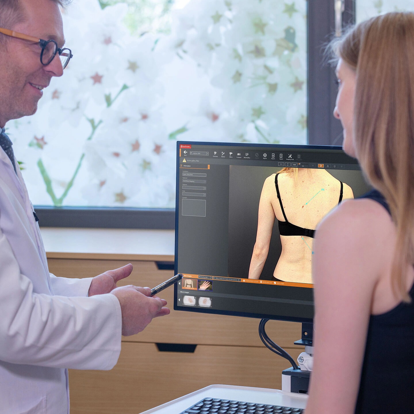 A clinician and patient review skin images at a FotoFinder workstation.