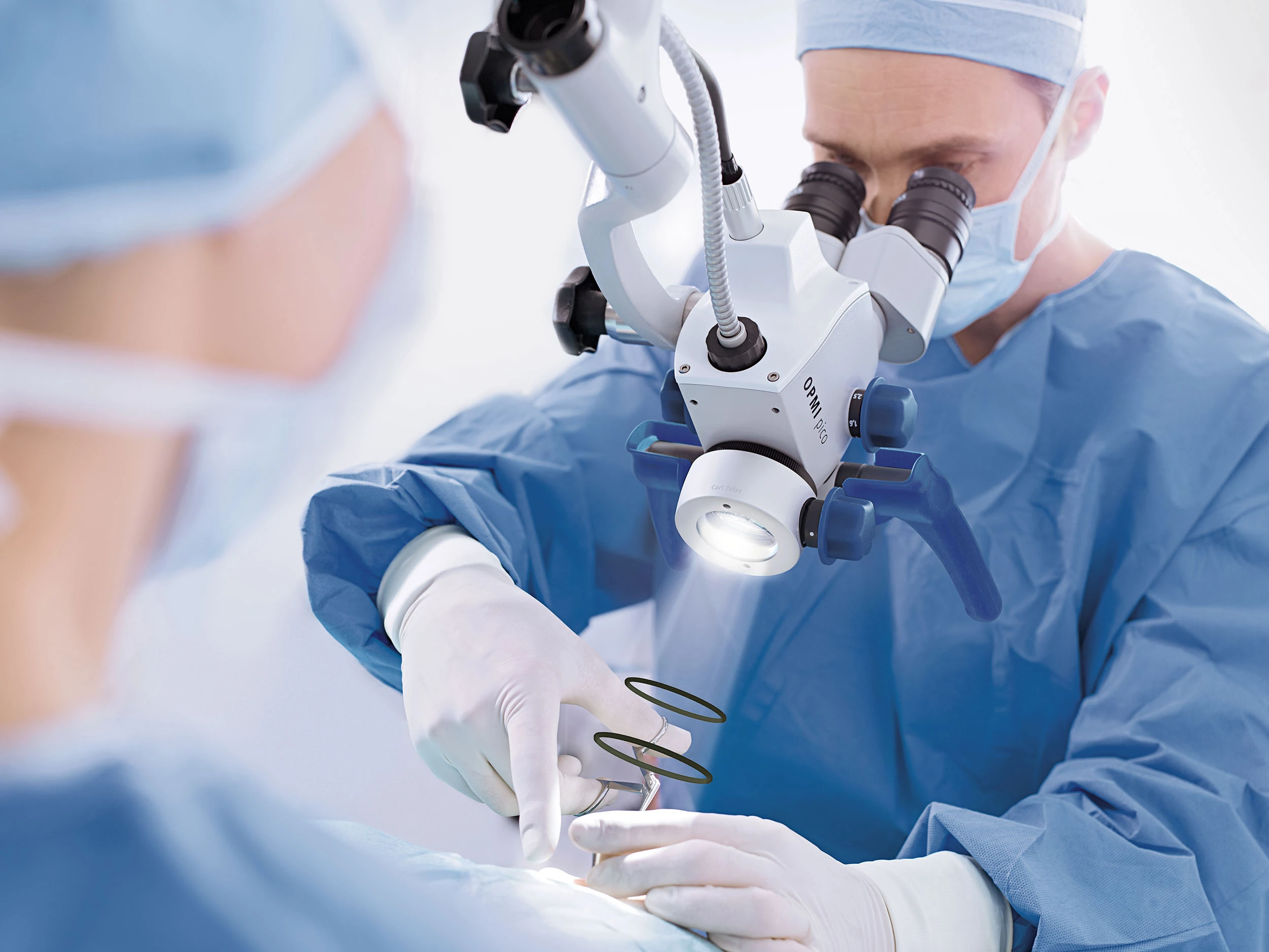 A clinician works through a ZEISS OPMI pico microscope during a procedure.