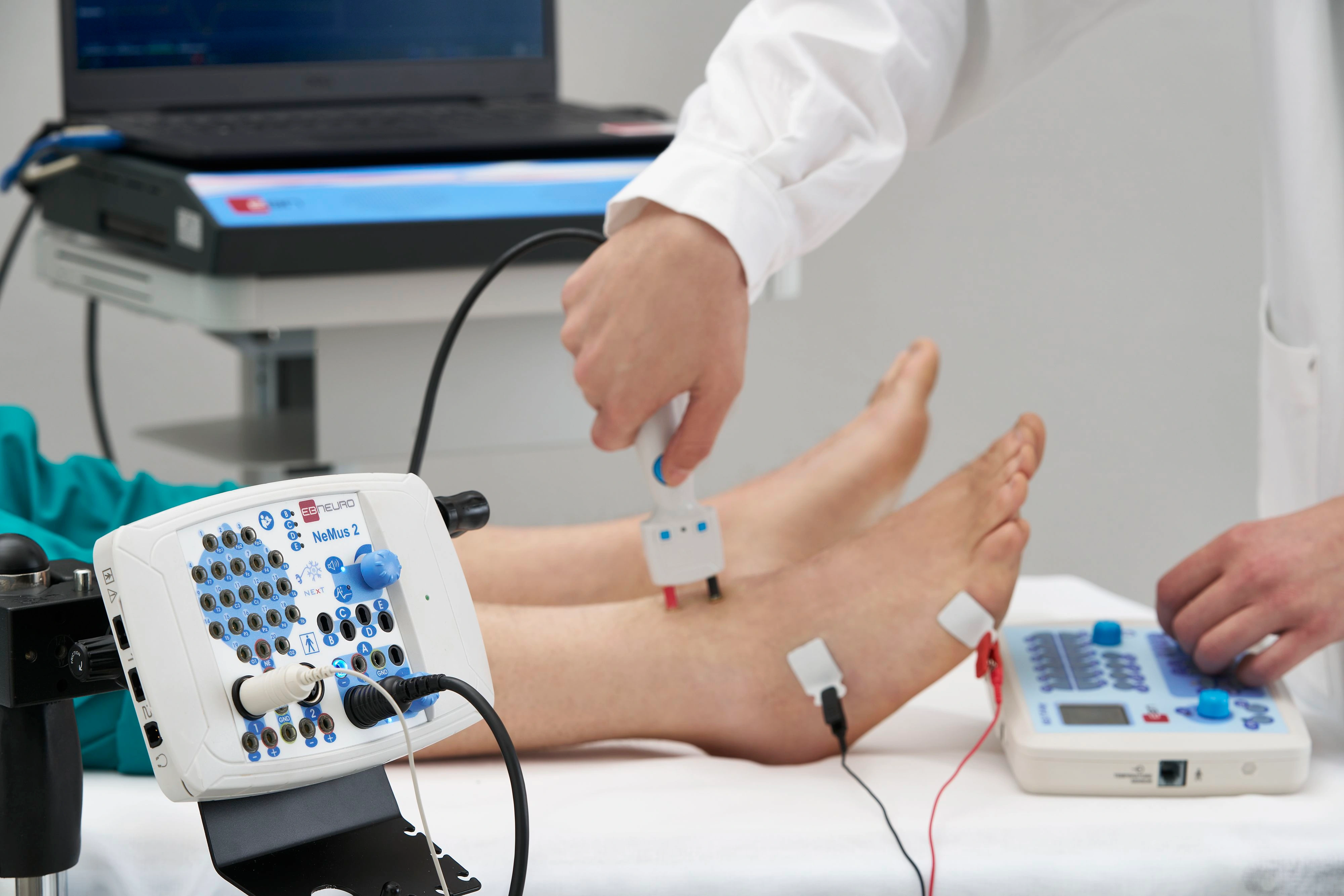 A clinician performs nerve conduction testing on a patient’s lower leg using an EB Neuro NeMus2 system.