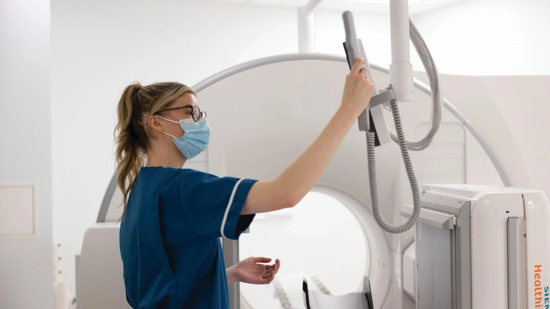A nuclear medicine technologist operates the gantry touchscreen on a Siemens Symbia Pro.specta system at Queen Elizabeth Hospital Birmingham.