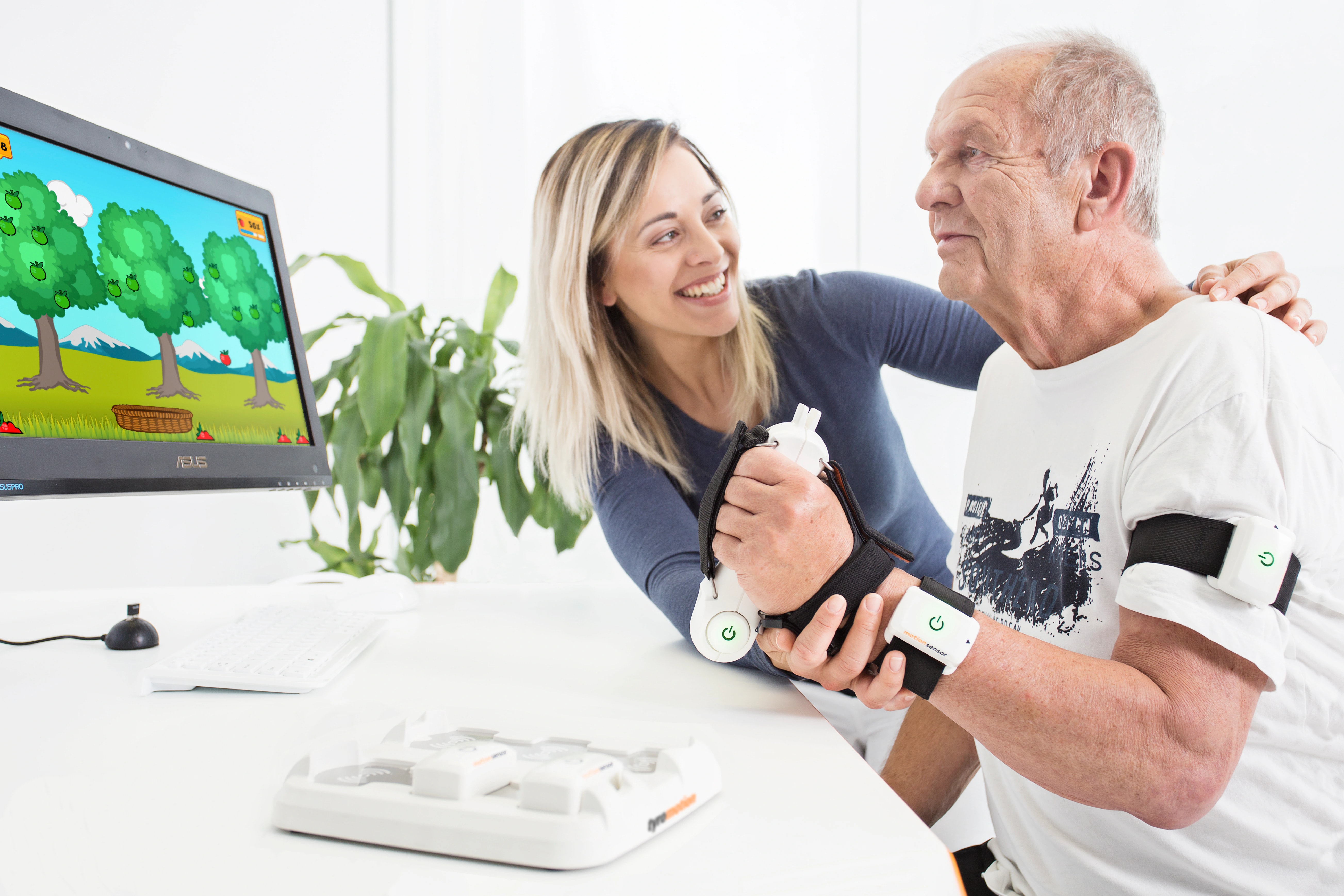 A therapist supports an adult patient using Tyromotion Pablo sensors during rehabilitation.