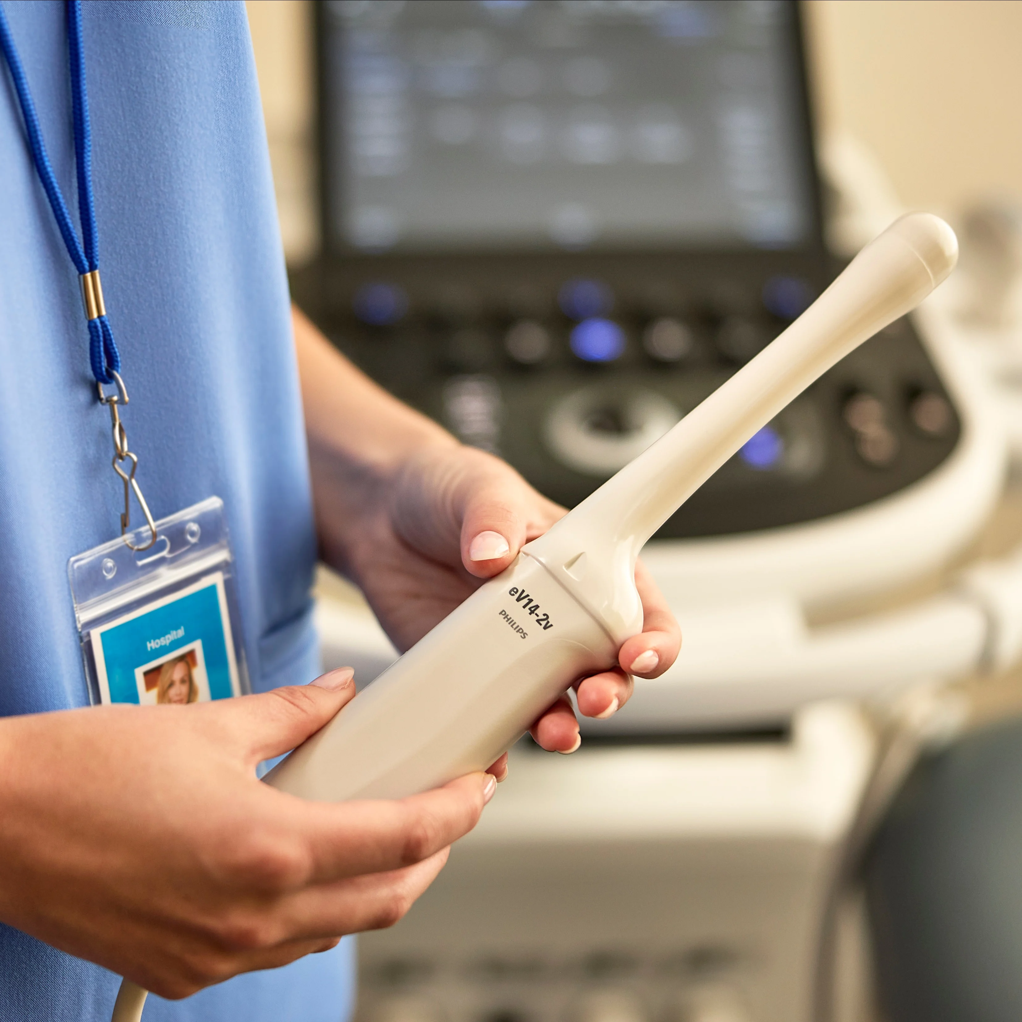 A clinician holds a Philips eV14-2v ultrasound transducer, with the ultrasound system in the background.