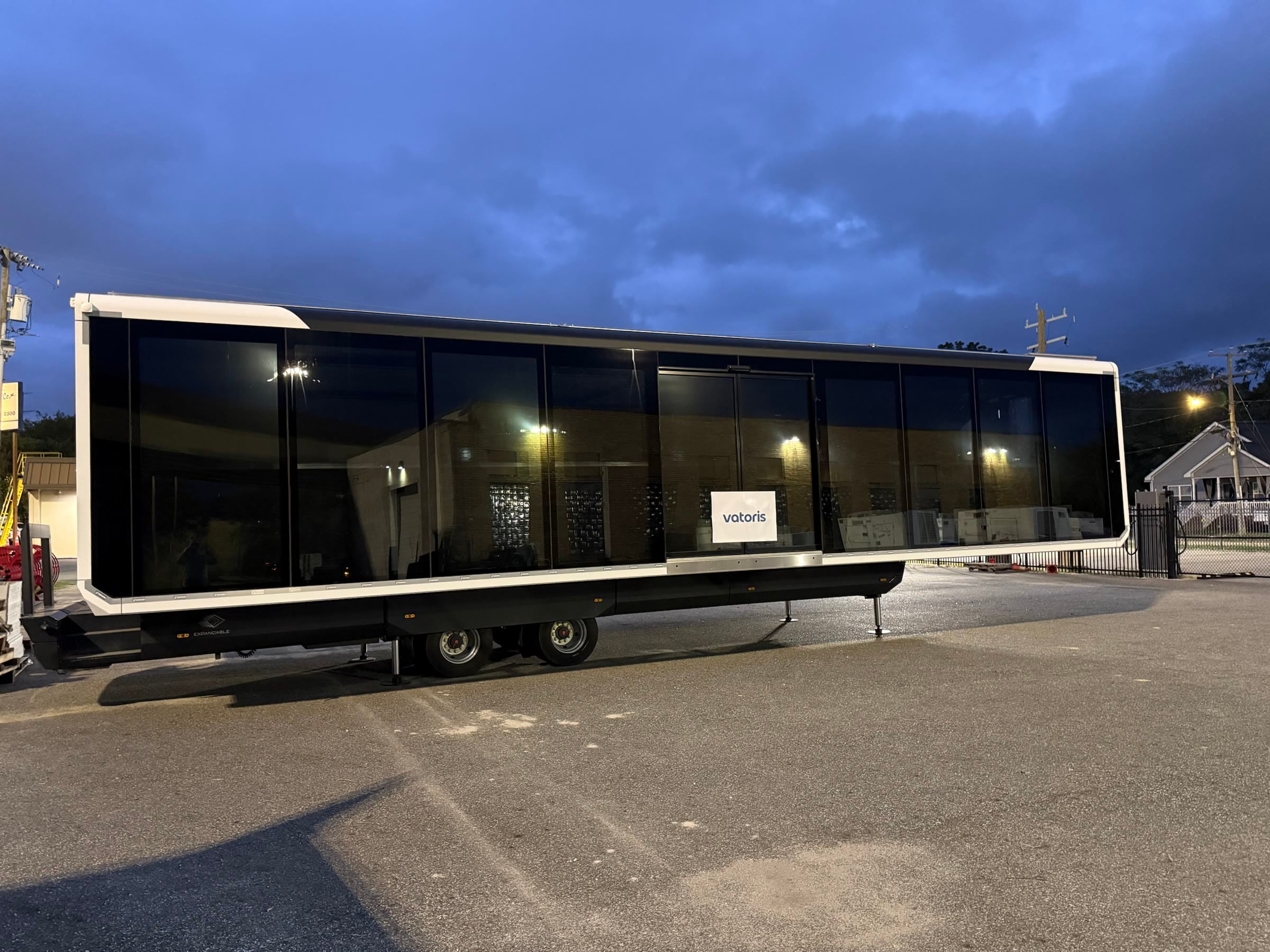Expandable unit at dusk in Norfolk, Virginia, its glass side lit, with a Vatoris sign in the window
