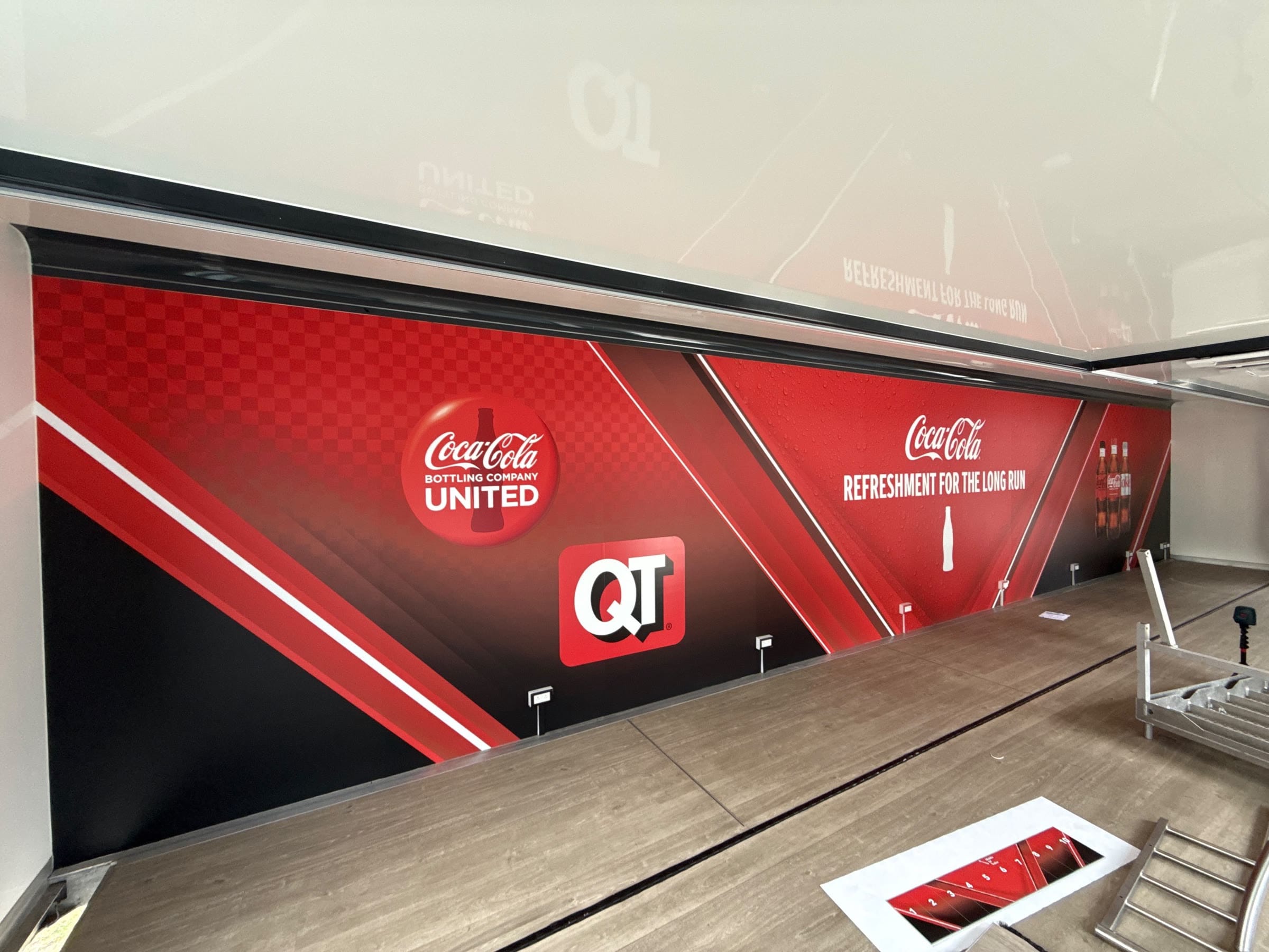 Inside the unit: a full-length wall wrapped in red and black graphics above a wood-effect floor