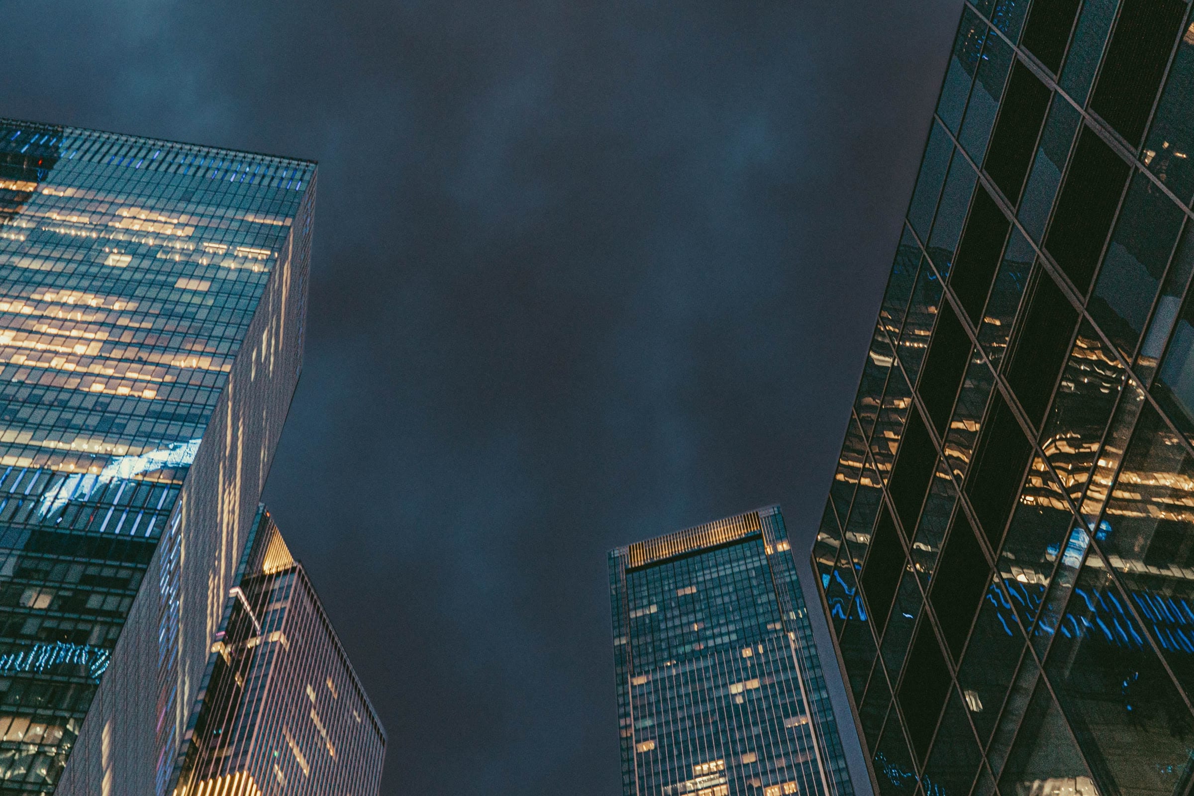 Looking up between lit glass office towers at night